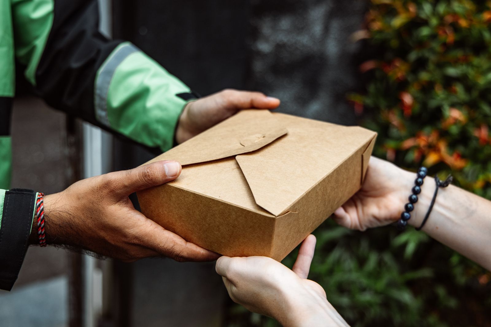 A kraft parcel handed from courier to buyer